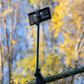 A phone mounted to the court fence with SwingVision’s support hardware.